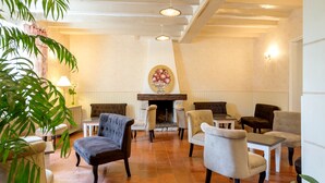 Un hall d’entrée avec une cheminée, plusieurs fauteuils, une table et des plantes en pot.