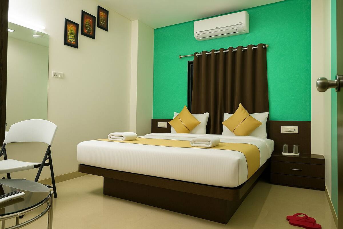 A hotel room with a bed, a chair, an air conditioner, and a nightstand.