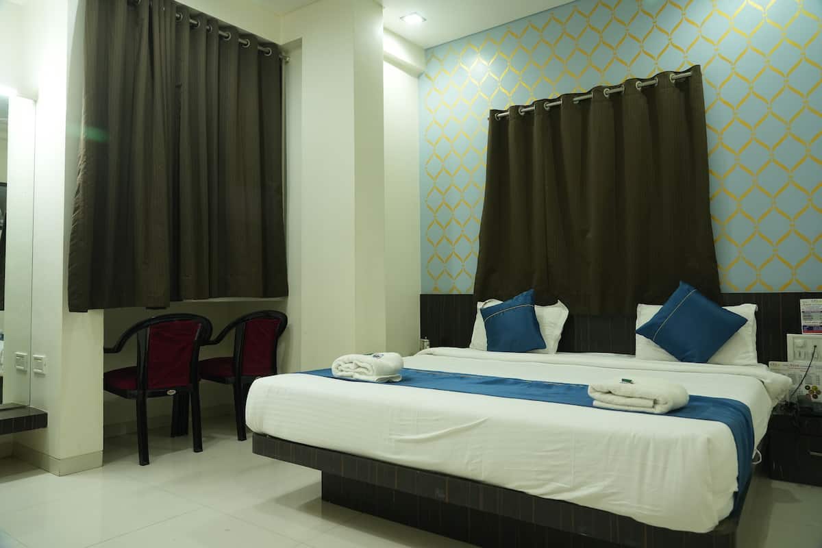 A hotel room with a large bed, two chairs, a nightstand, and a wall with a geometric pattern.