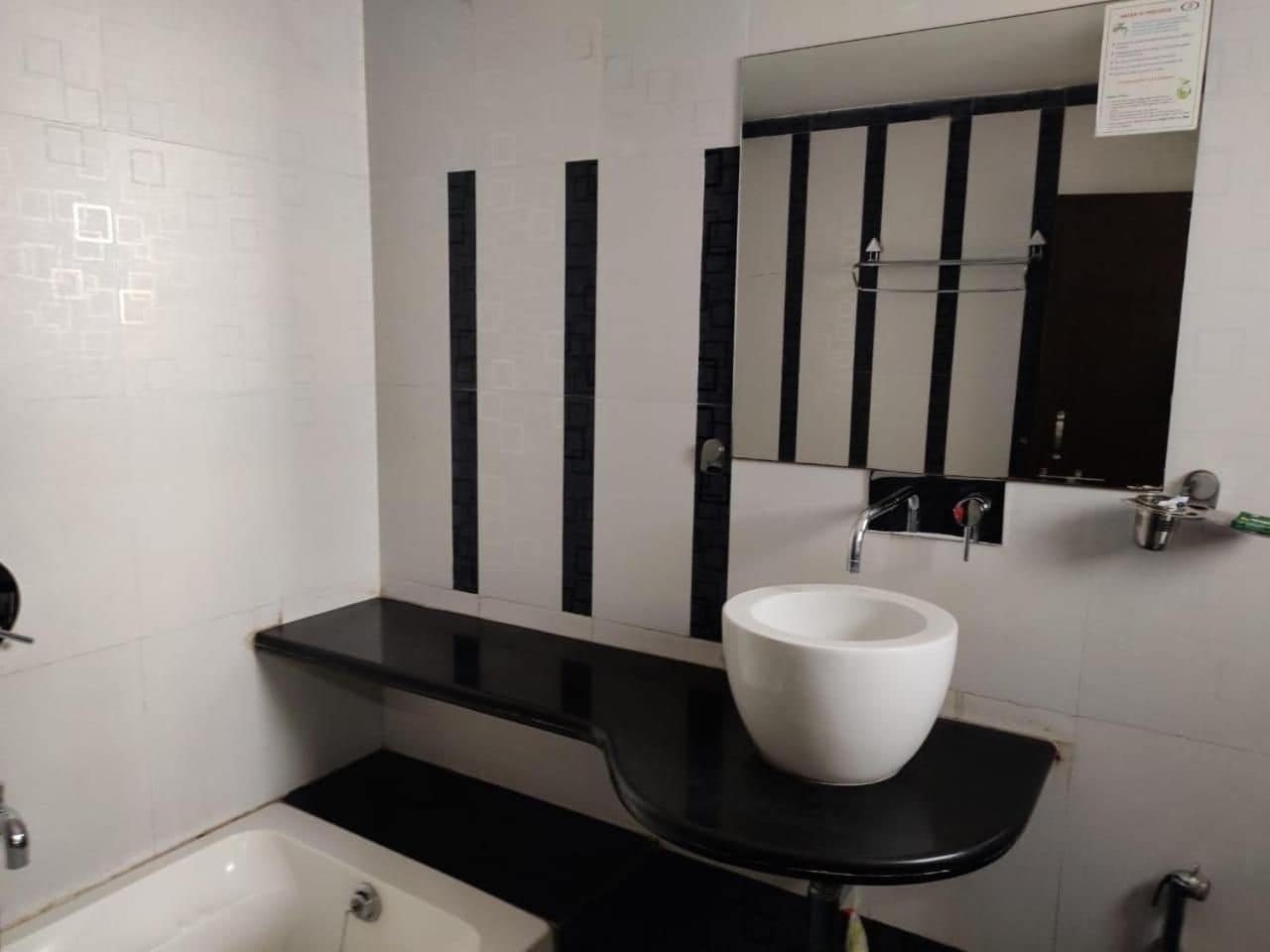 A bathroom with a white sink, black countertop, and a mirror above it.