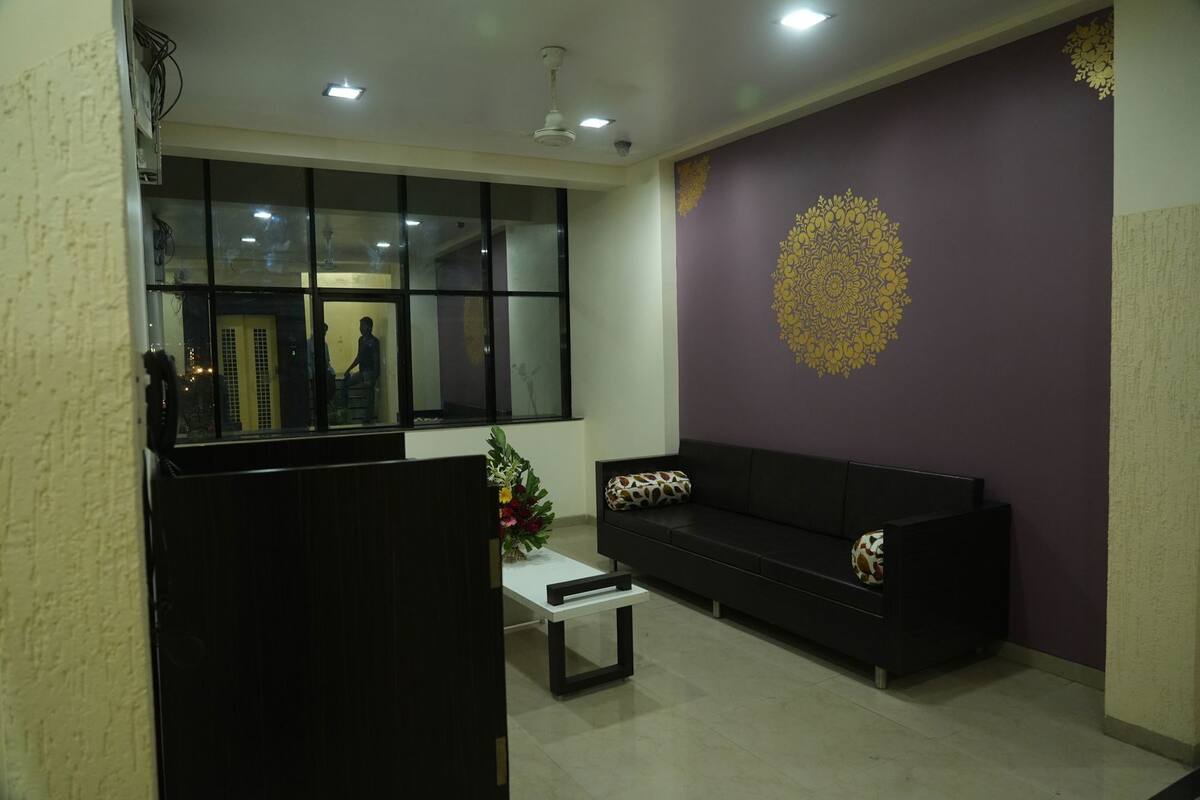 A room with a sofa, a small table, a decorative wall, and a window with reflections.
