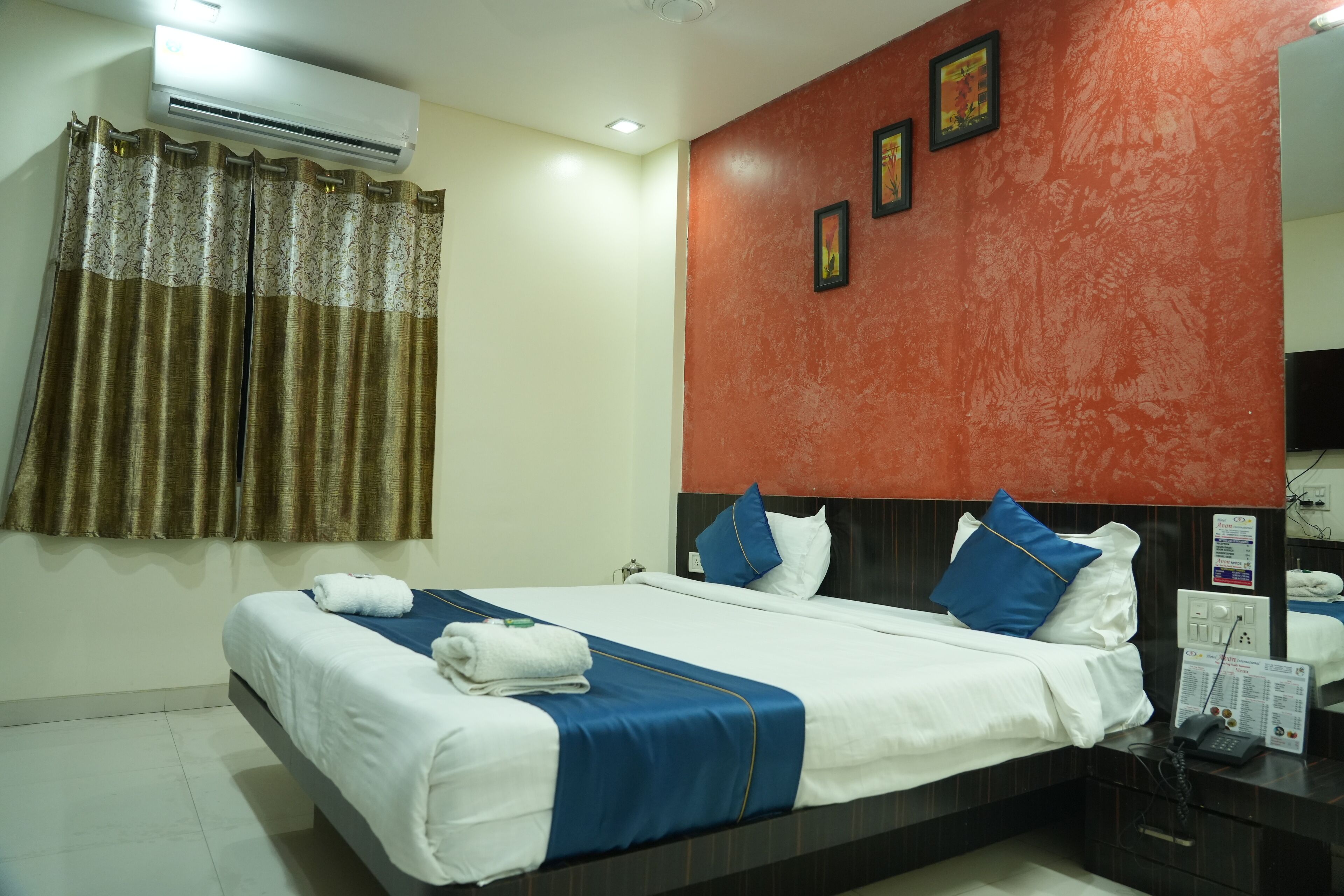 Habitación de hotel con cama, mesita de noche, aire acondicionado y una pared con cuadros.