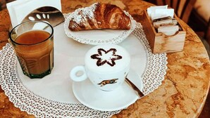Un tavolo con un croissant, una tazza di caffè e un astuccio di fazzoletti.
