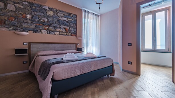 Una camera da letto moderna con una parete in pietra, un letto grande con lenzuola rosa e pavimento in legno.