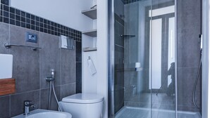 Un bagno moderno con doccia vetro-murata, vasca freestanding e water.