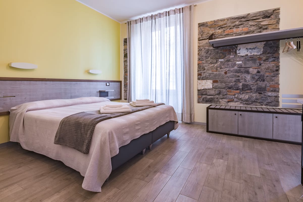 Ein Schlafzimmer mit Bett, Holz-Kopfteil, Steinwand, integriertem Regal und Holzboden.
