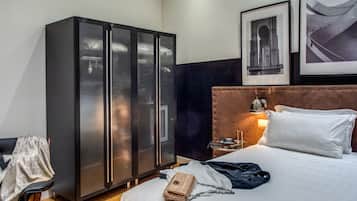 Camera d'albergo con un letto, un armadio, un comodino e una sedia.