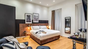 Una habitación de hotel moderna con una cama grande, una mesita de noche con lámpara, una silla y un televisor.