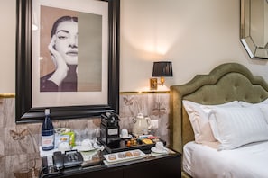 A neatly arranged hotel room with a bed, a bedside table with a phone, a framed picture, a lamp, and a coffee maker. - The Talent Hotel (Rome)