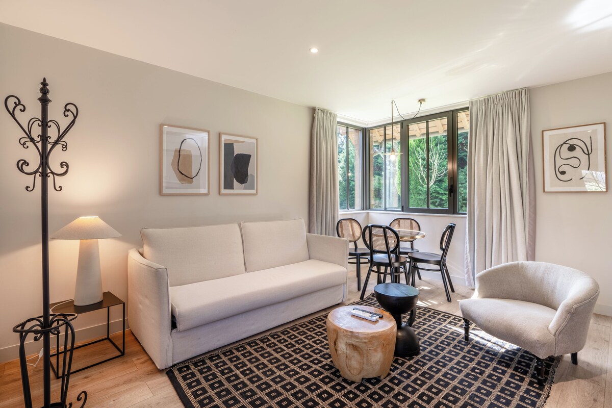 Una sala moderna con sofá, sillón, mesa de centro y un comedor con sillas y una mesa.