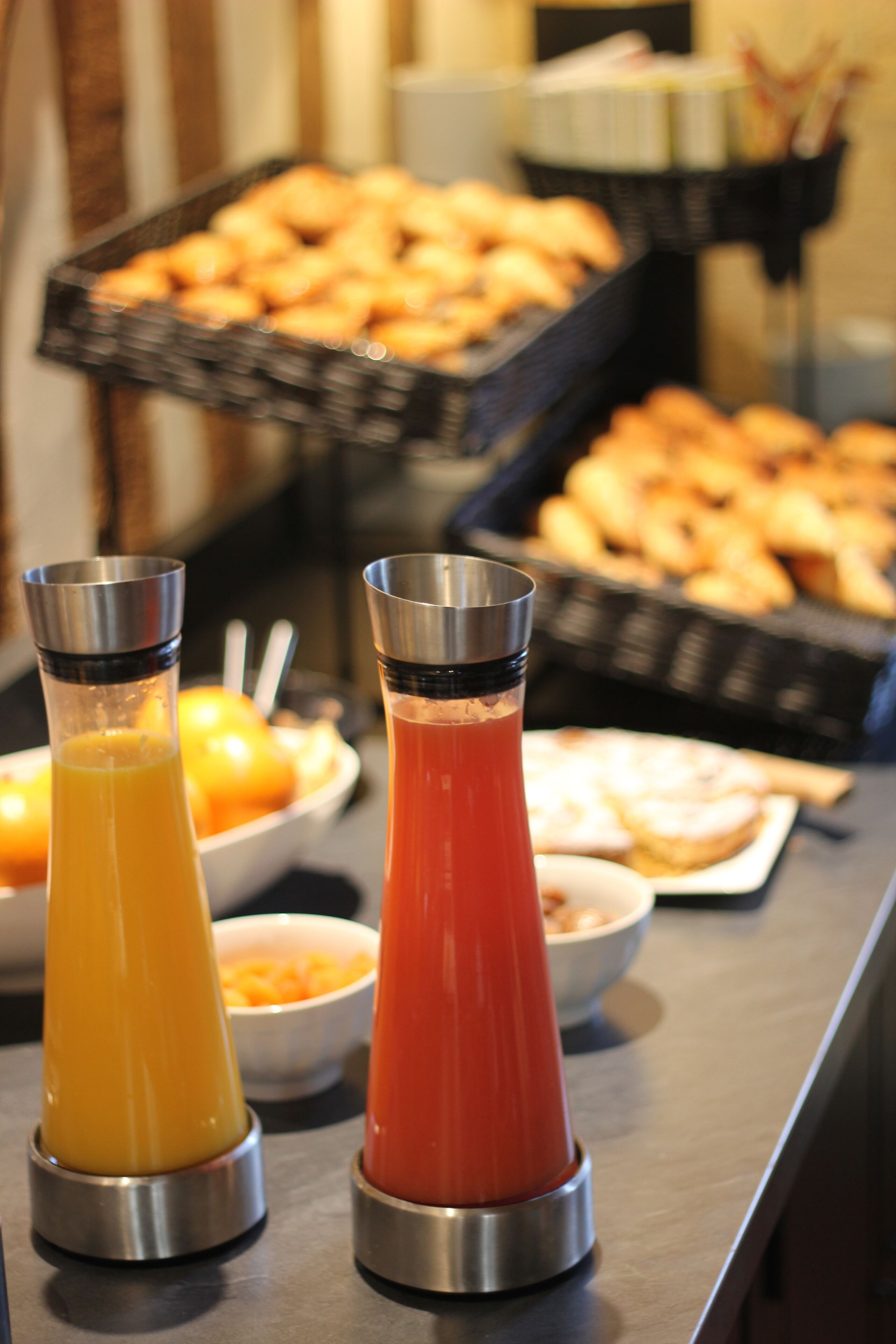 Un bufé con diversos alimentos y dos dispensadores de jugo.