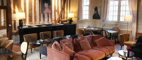 A cozy room with a brown sofa, multiple chairs, a dining table, and a window with curtains.