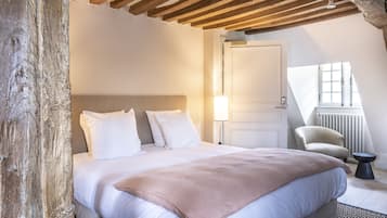 Un dormitorio con una cama grande, techo de madera, una silla y una ventana.
