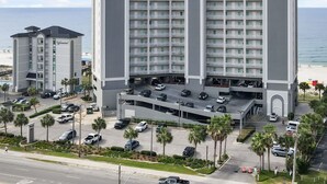 Un hotel de gran altura con varios balcones, un estacionamiento y vistas a la playa.