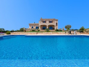 Une maison en pierre à deux étages avec une piscine devant.