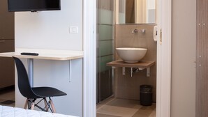A modern bathroom with a large mirror, a white sink, and a shower. - Lobby Collective Hostel (Lecce)
