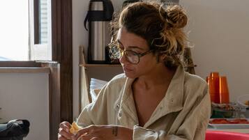 Une personne est assise à une table devant un sandwich, une machine à café et une chaise rouge se trouve à l’arrière-plan.