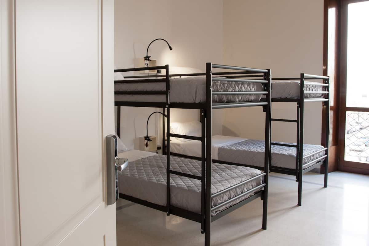 A bunk bed room with a desk and lamp.