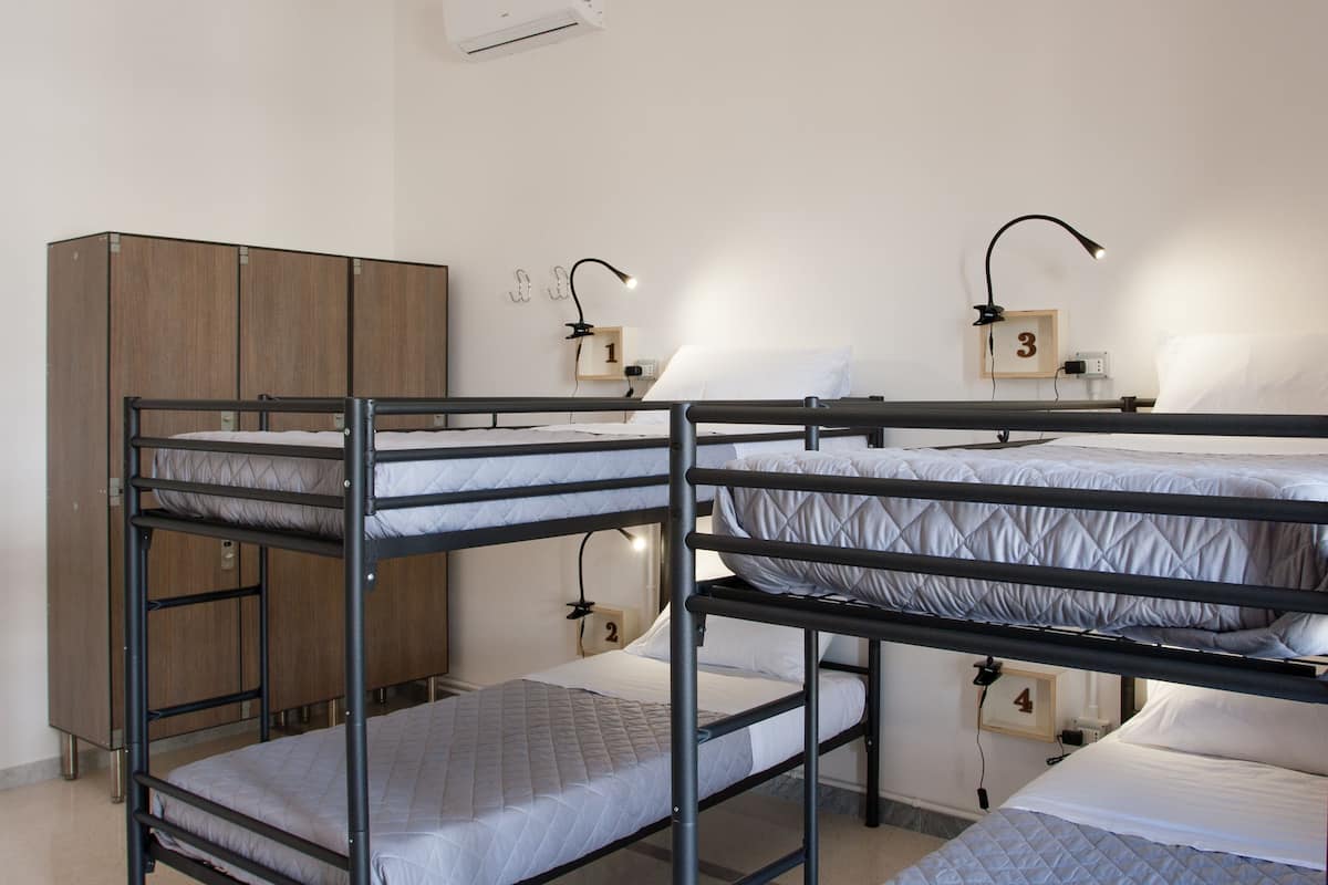 A dormitory room with bunk beds, a wardrobe, and a wall-mounted air conditioner.