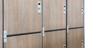 A row of wooden lockers with metal handles and numbered lockplates. - Lobby Collective Hostel (Lecce)