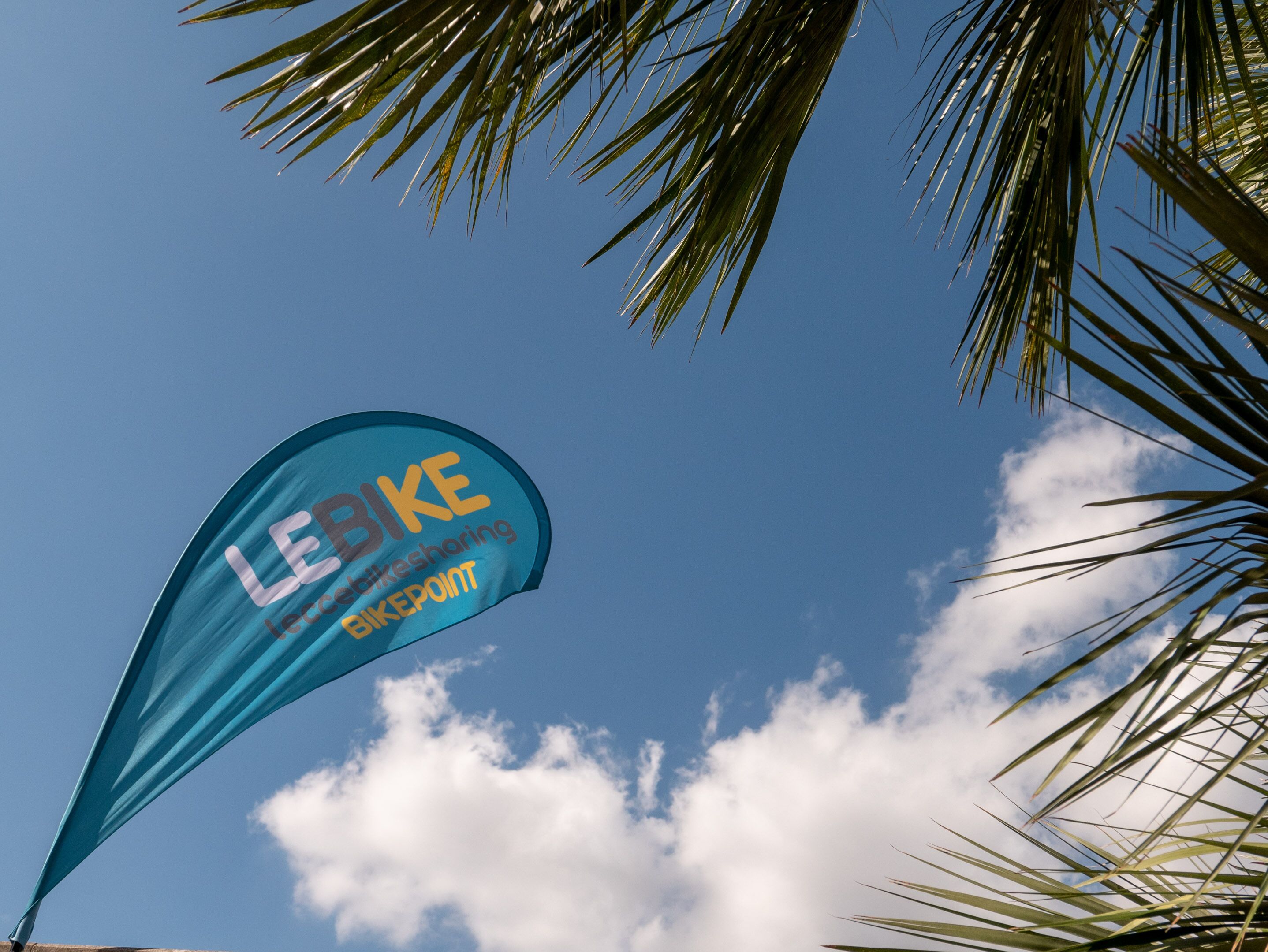 A clear blue sky with a banner featuring the text "LEBIKE" and "bike sharing" against it.