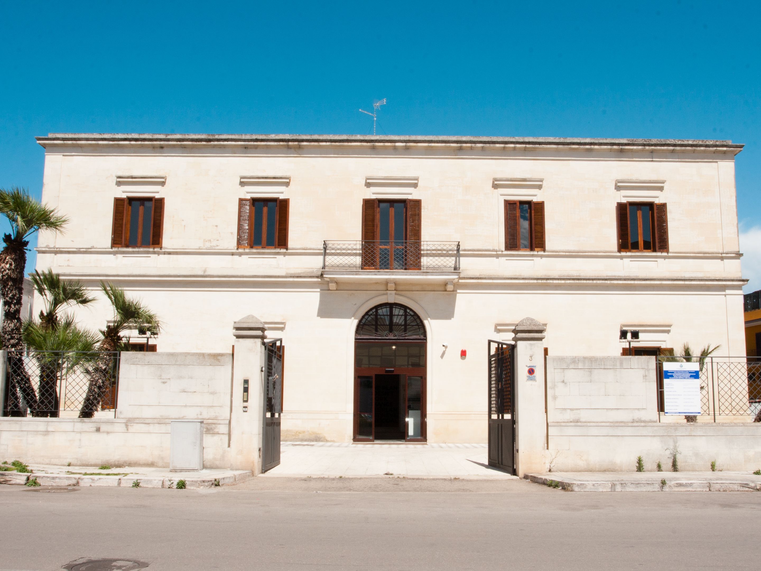 Un bâtiment à deux étages doté d’une façade symétrique, d’une entrée centrale avec une porte en arc de cercle et d’un balcon à l’étage supérieur.