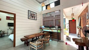 Een eethoek met een houten tafel en stoelen, een keuken met een fornuis en aanrecht, en een meterkantige bakstenen muur met een raam.