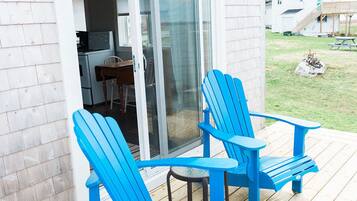 Een houten terras met twee blauwe Adirondack-stoelen en een kleine tafel.