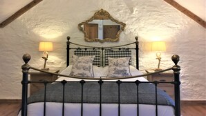 A bed with a metal frame, checkered bedding, and two bedside lamps. - Merlin Farm Daymer and Treyarnon (Newquay)