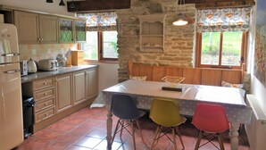 A kitchen with a wooden island, a refrigerator, and a window with a view of greenery. - Merlin Farm Daymer and Treyarnon (Newquay)