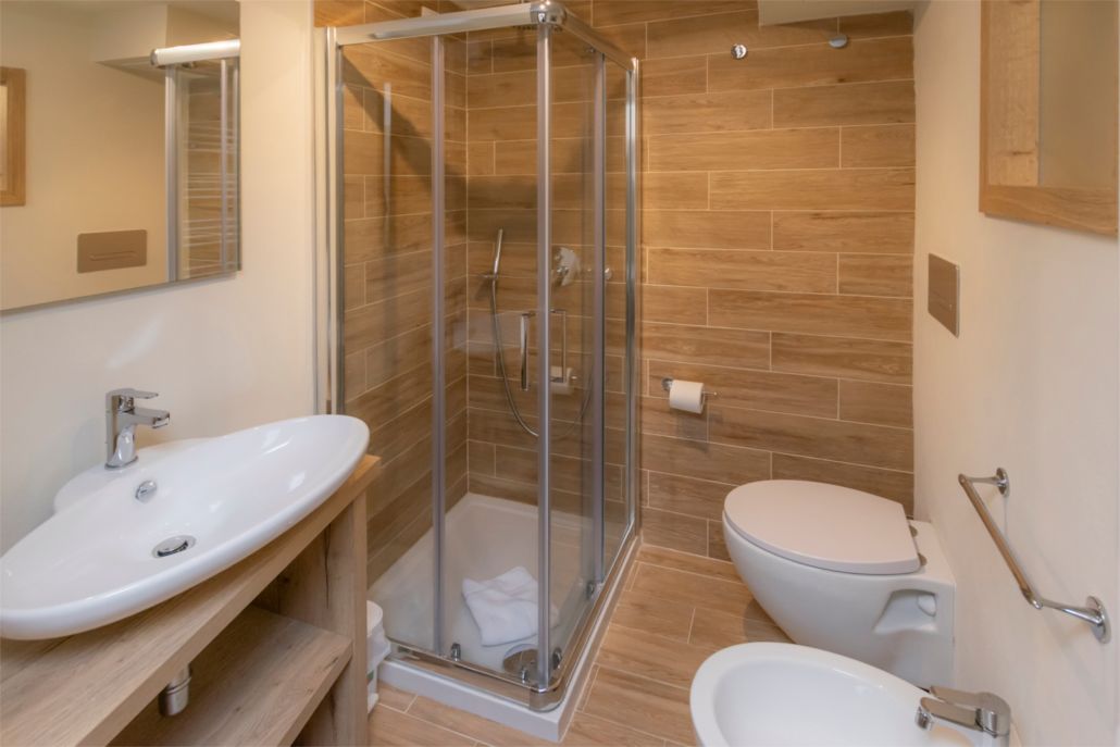 A modern bathroom with a glass-enclosed shower, a sink, and a toilet.