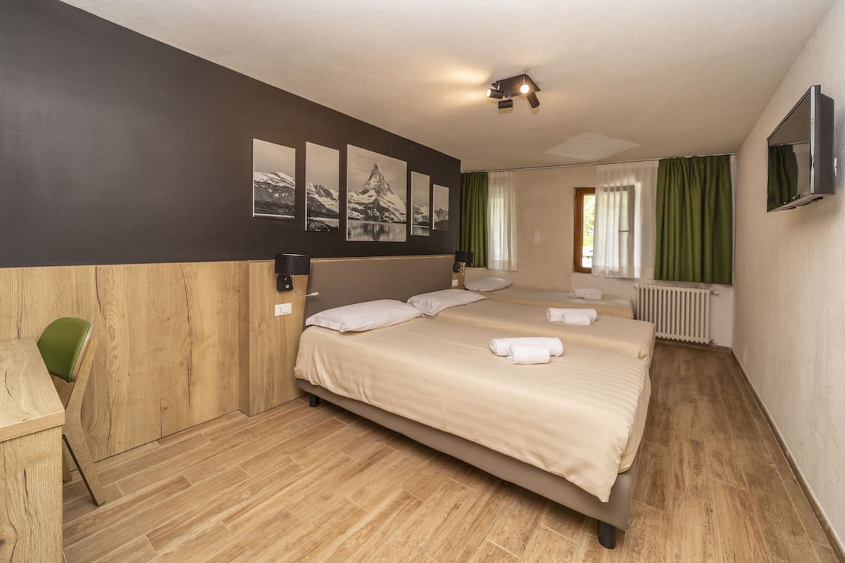 A hotel room with a large bed, a desk, and a TV.