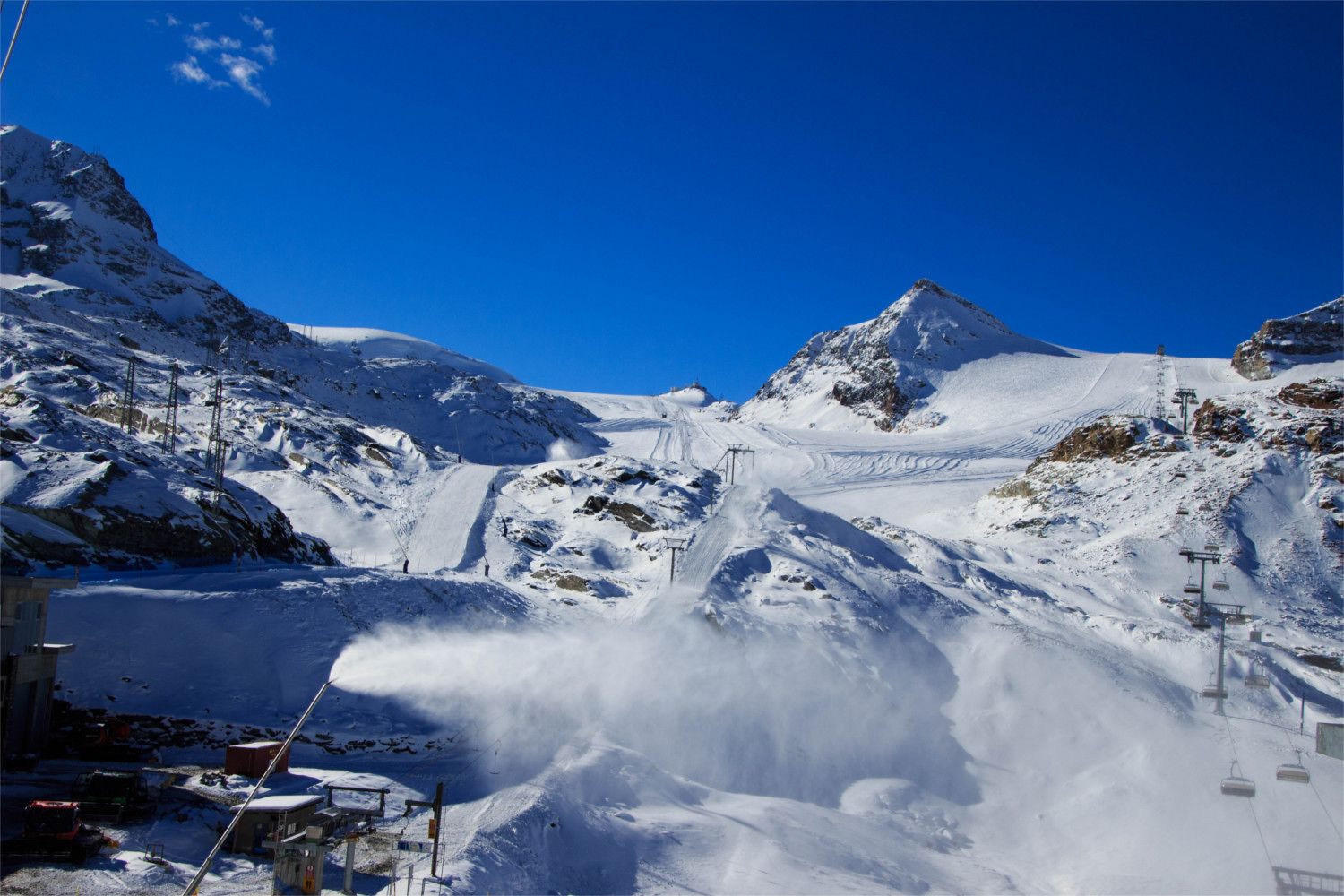 A snowy mountain landscape with ski lifts and a clear blue sky.