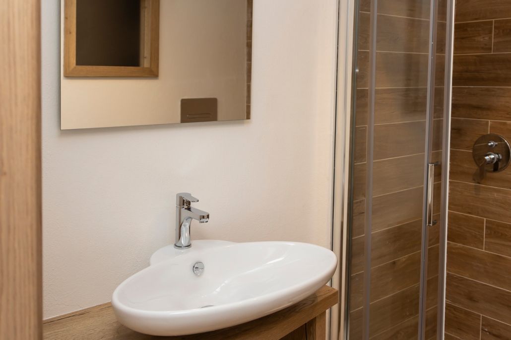 A bathroom with a white sink, a mirror, and a glass shower enclosure.