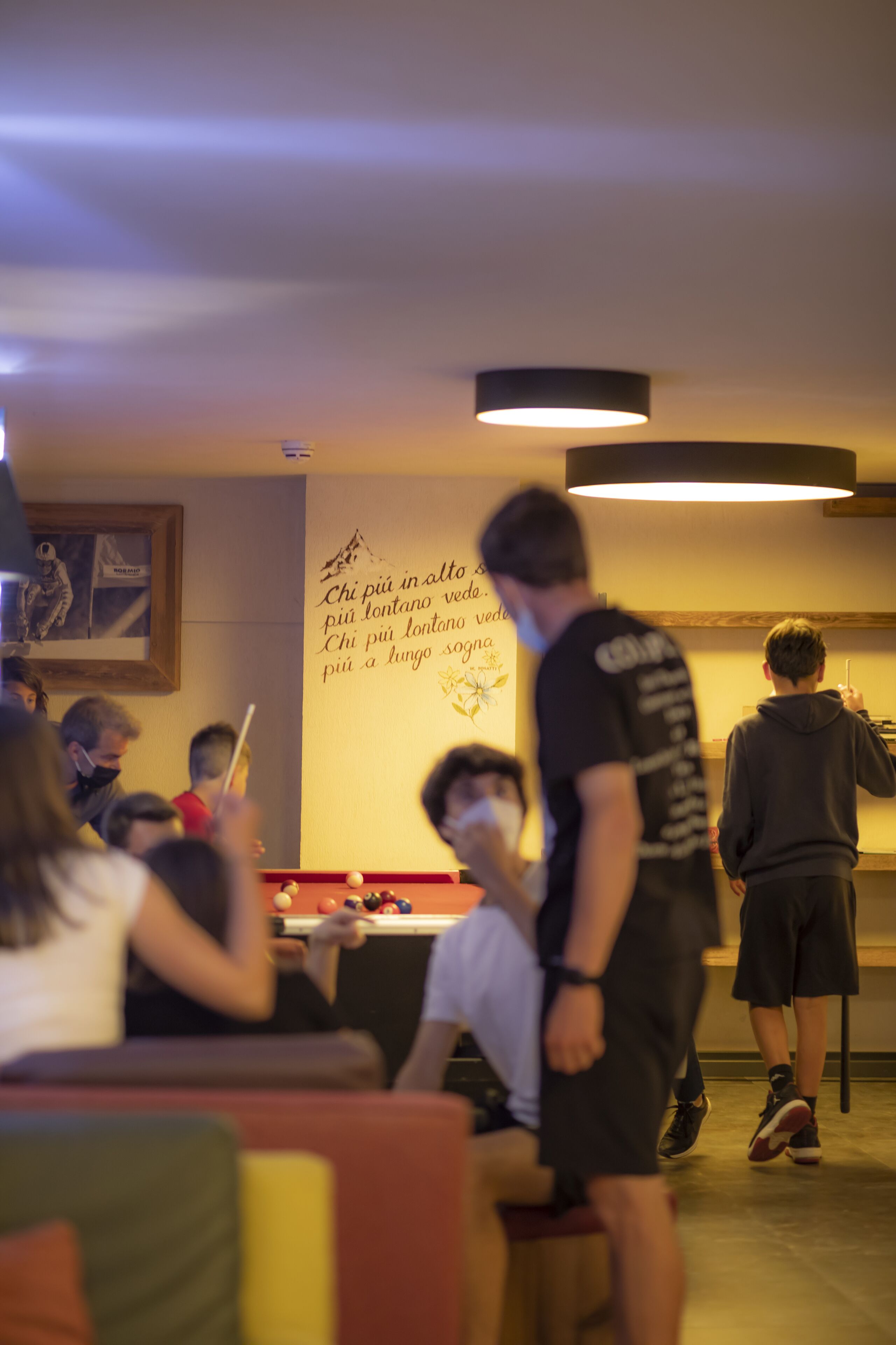 Una mesa de billar en una sala con un mural en la pared y una lámpara en el techo.