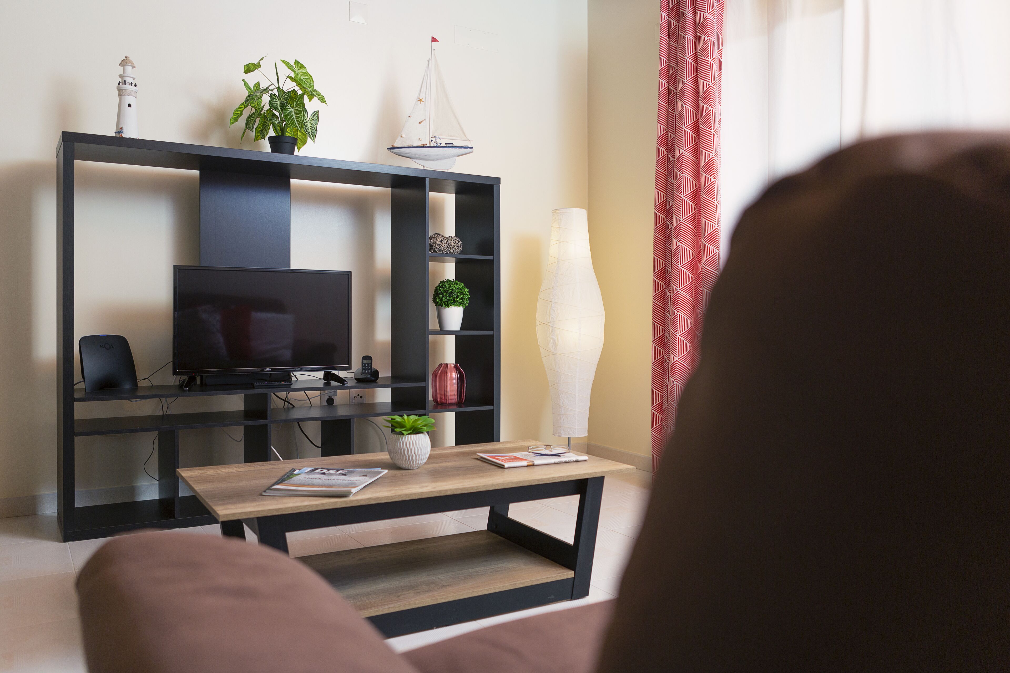 A modern living room with a TV, a wooden coffee table, and a black entertainment unit with decorative items.