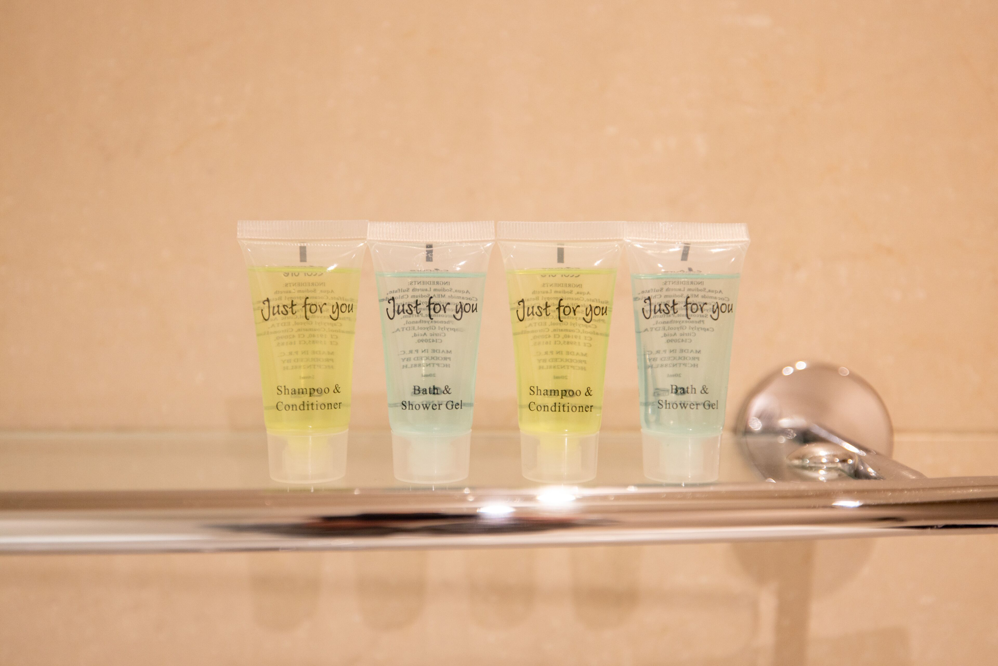 Four toiletries on a bathroom shelf.