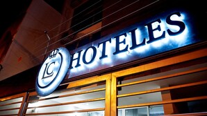Un letrero de hotel con letras iluminadas que deletrean "HOTELES" y un logotipo con "LC" y un símbolo de corona.
