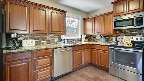 A modern kitchen with wooden cabinets, stainless steel appliances, and a tiled backsplash. - Pueblo House by Riverwalk, 2 Miles to Fairgrounds! (Pueblo)