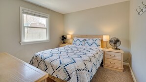 A bedroom with a bed, bedside tables, a desk, a window, and a ceiling light. - Pueblo House by Riverwalk, 2 Miles to Fairgrounds! (Pueblo)