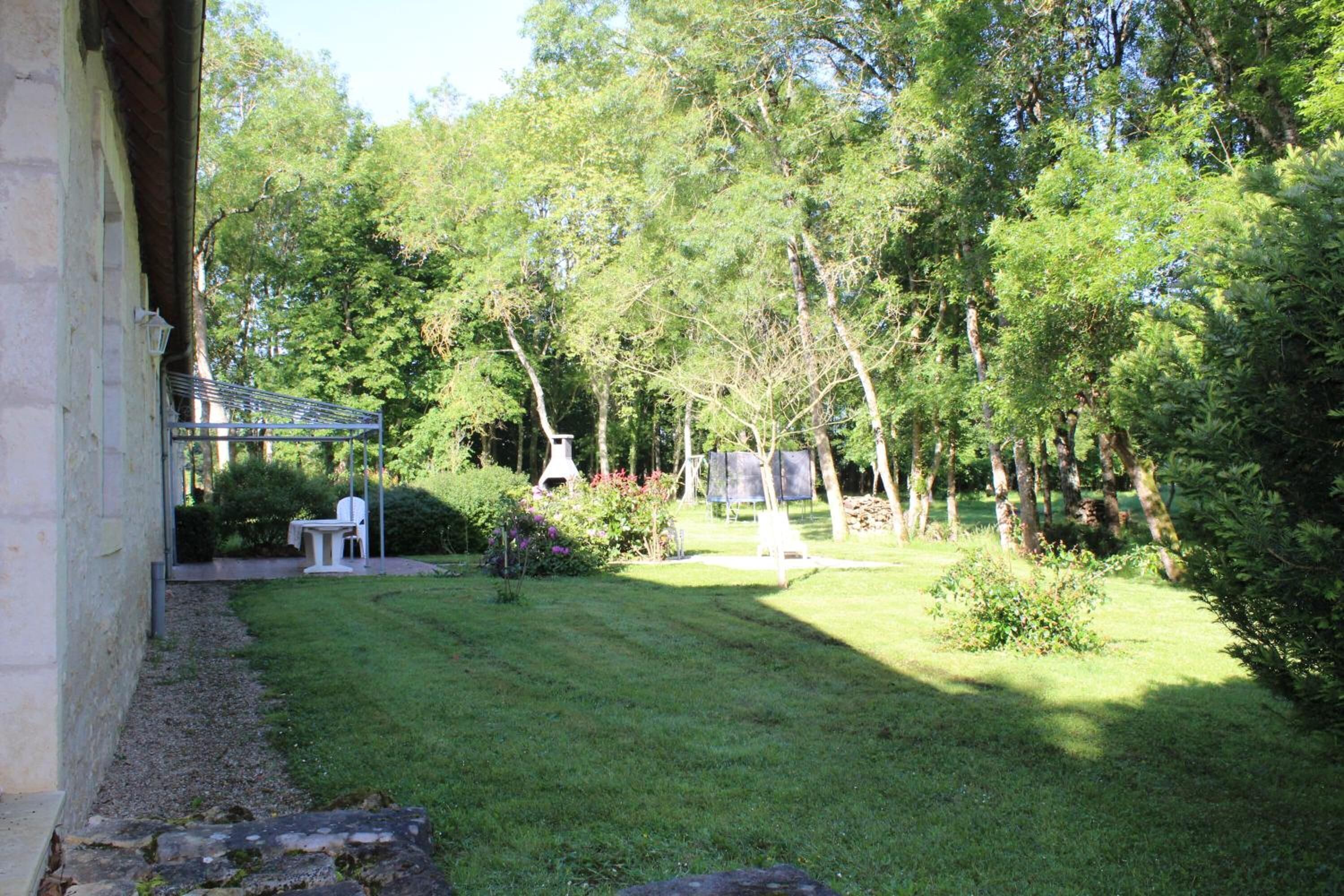 A well-maintained garden with a lawn, a small table and chair, and a gazebo.