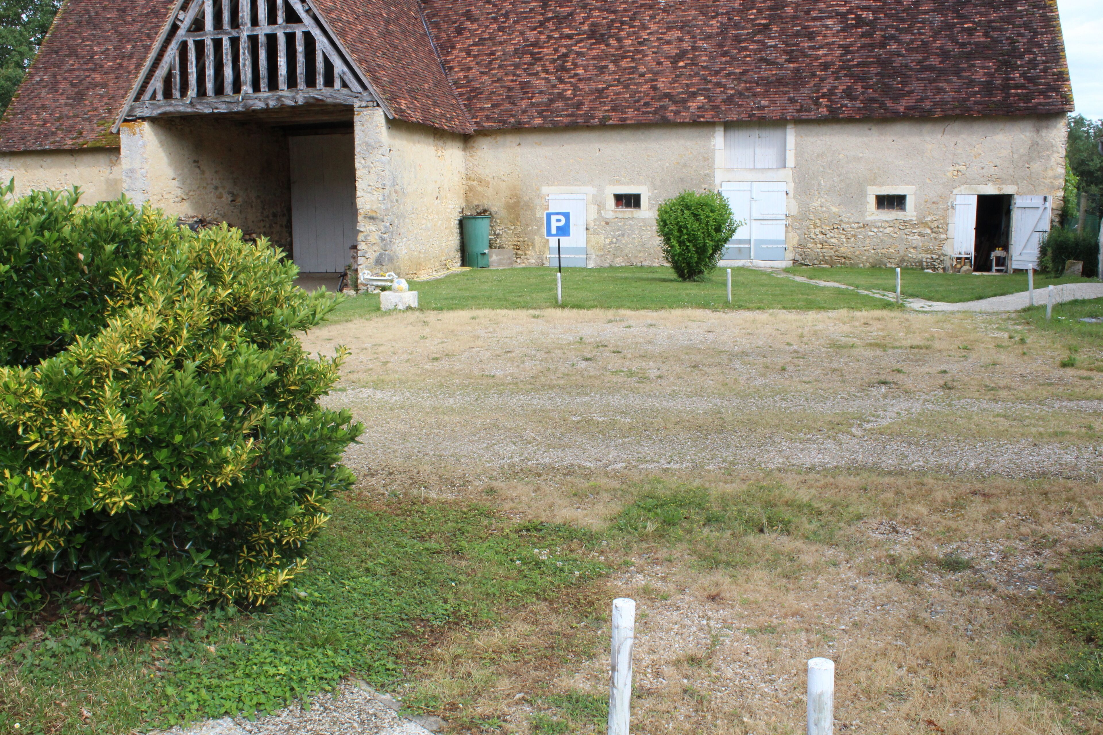 A rustic building with a stone facade, a traditional pitched roof, and a small garden area in front.