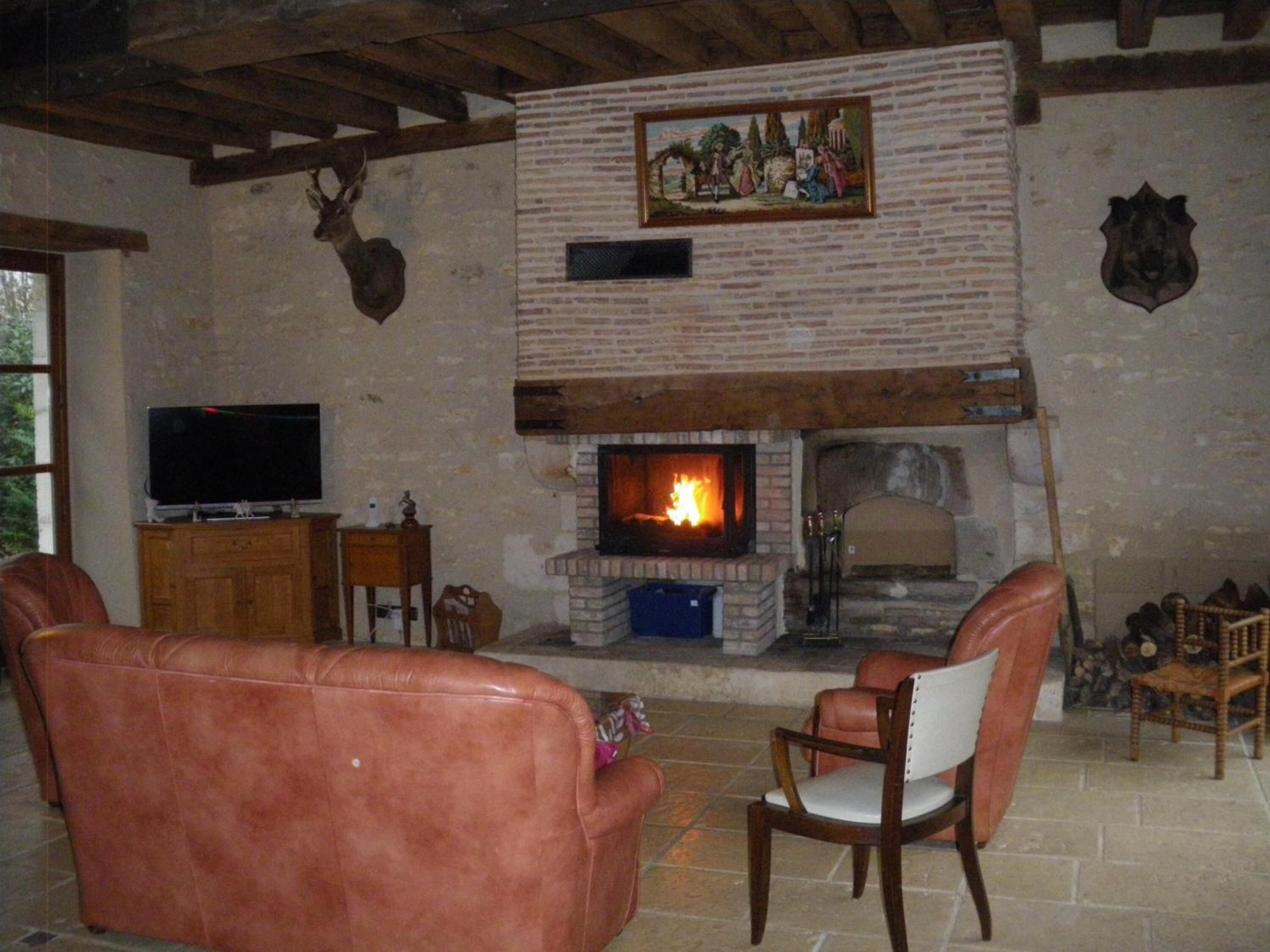 Ein rustikales Wohnzimmer mit Kamin, Ledersofas und einem Fernseher.