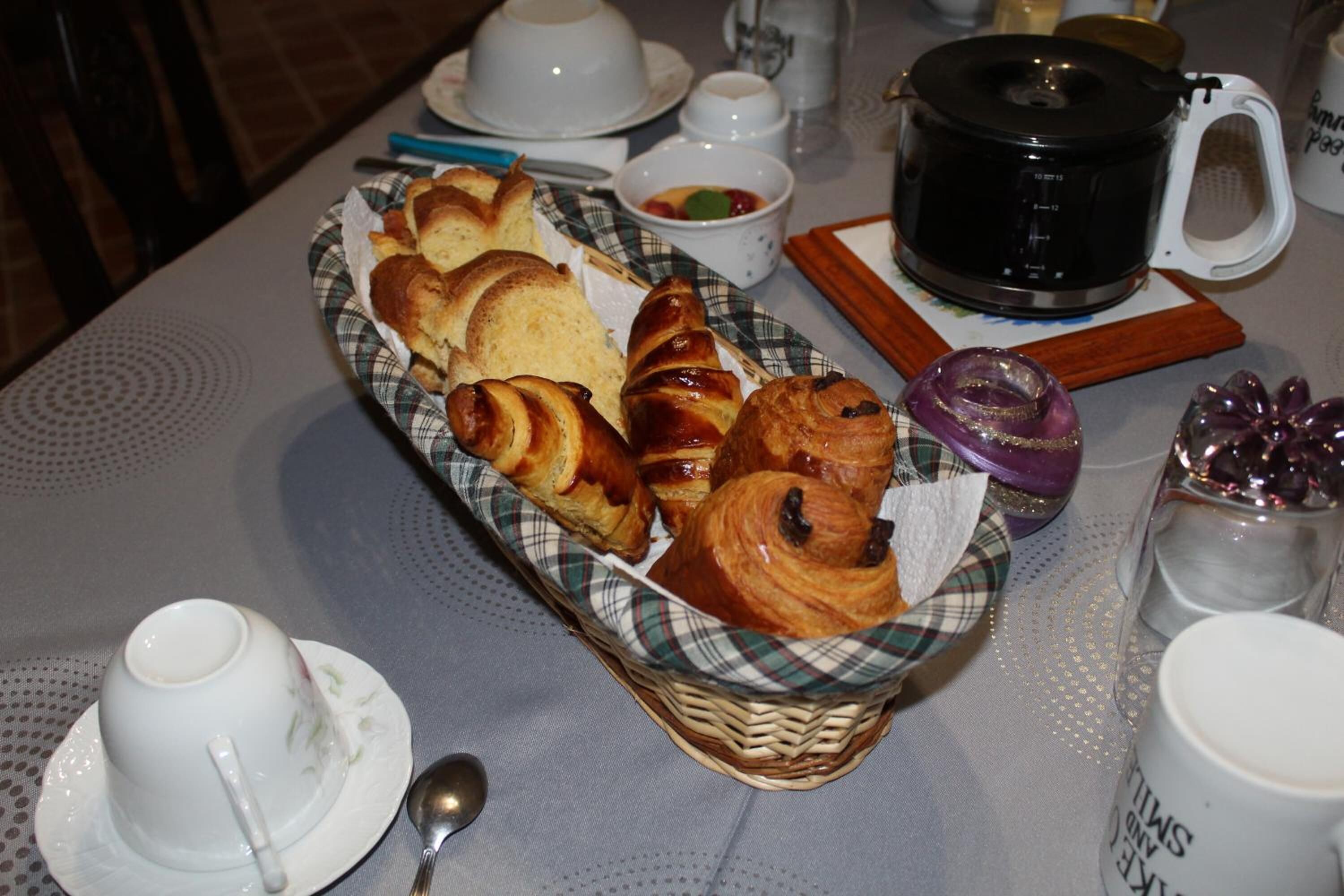 Una mesa de desayuno con cruasanes, una cafetera y diferentes acompañamientos.