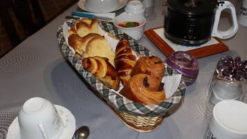 Una mesa de desayuno con cruasanes, una cafetera y diferentes acompañamientos.