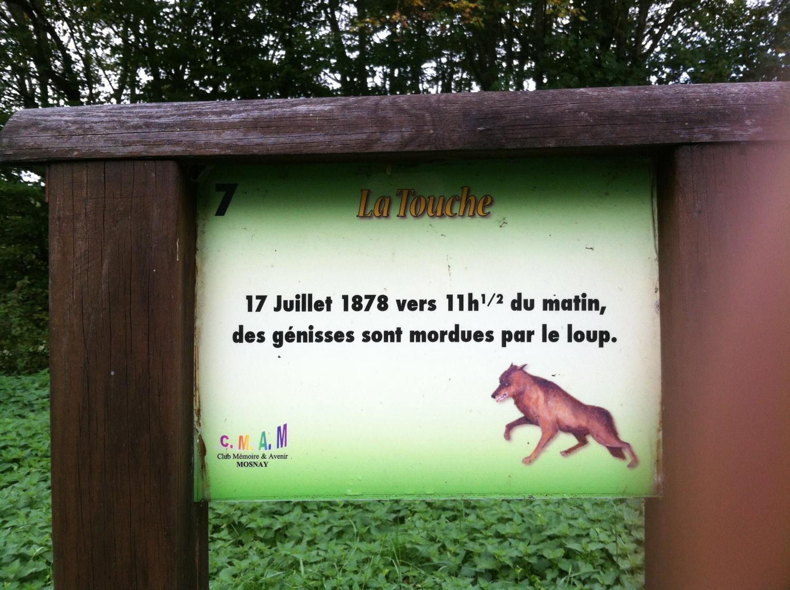 A historical marker with a date and event description, a logo, and an illustration of a dog.