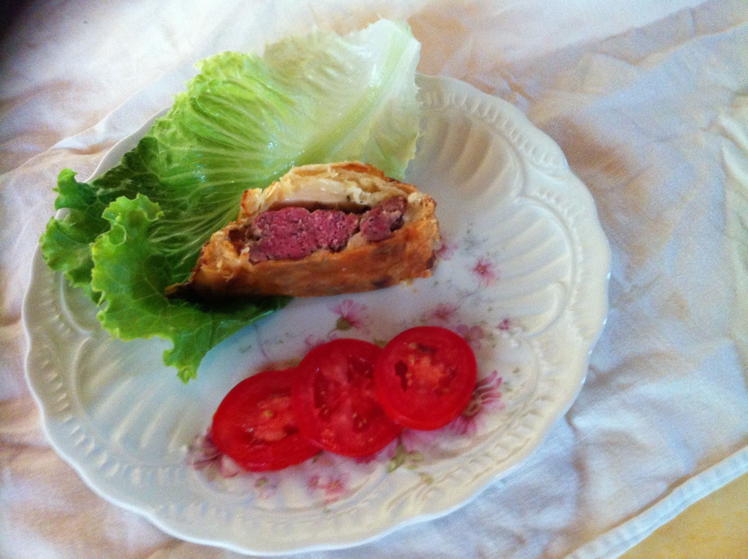 Un plato con un sándwich cortado por la mitad, lechuga y rodajas de tomate.