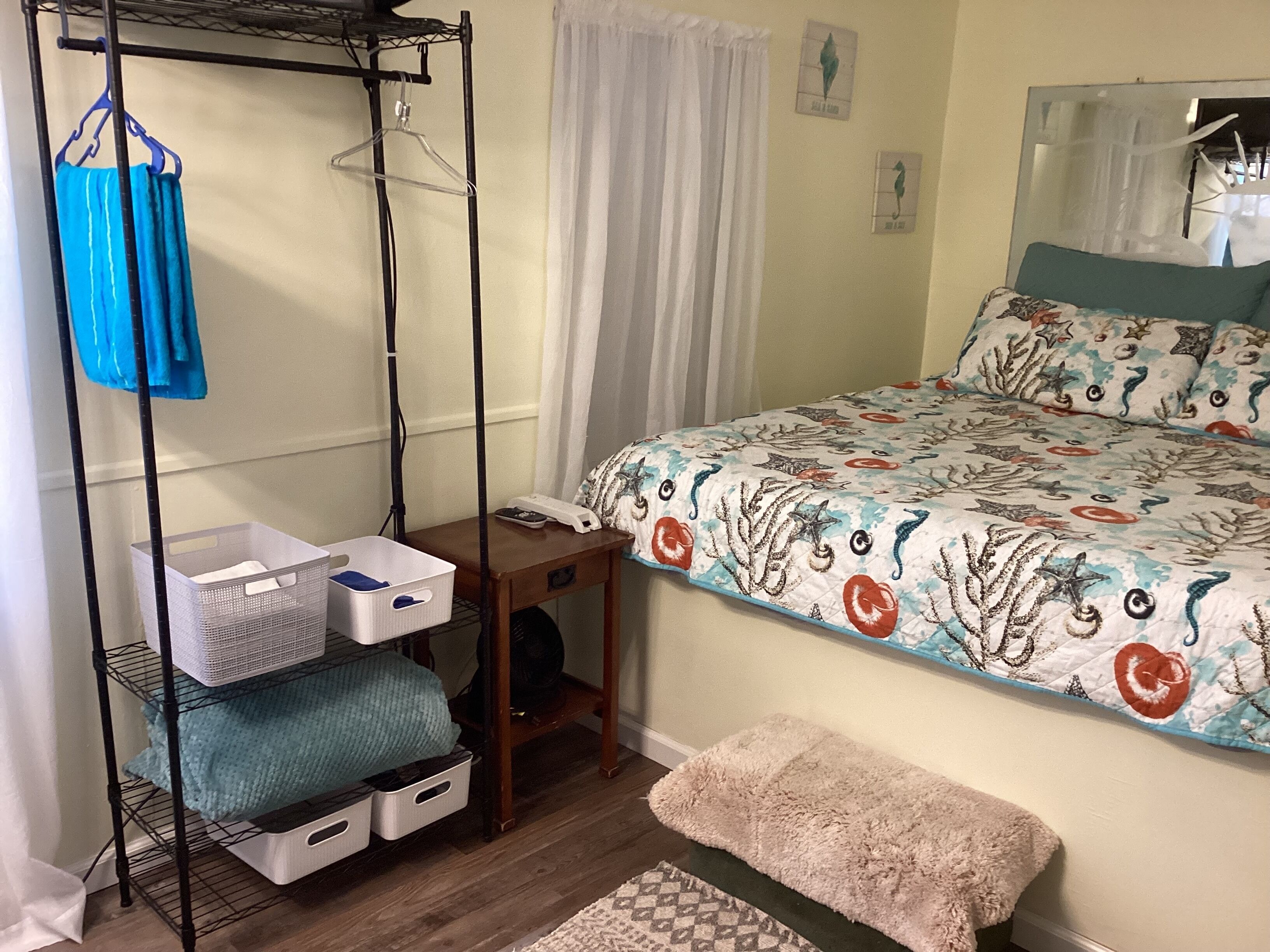 Een slaapkamer met een bed, een klein tafeltje, een kledingrek en een bank.