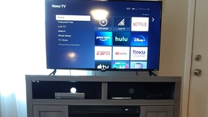 A Roku TV on a wooden entertainment center with a fireplace below.