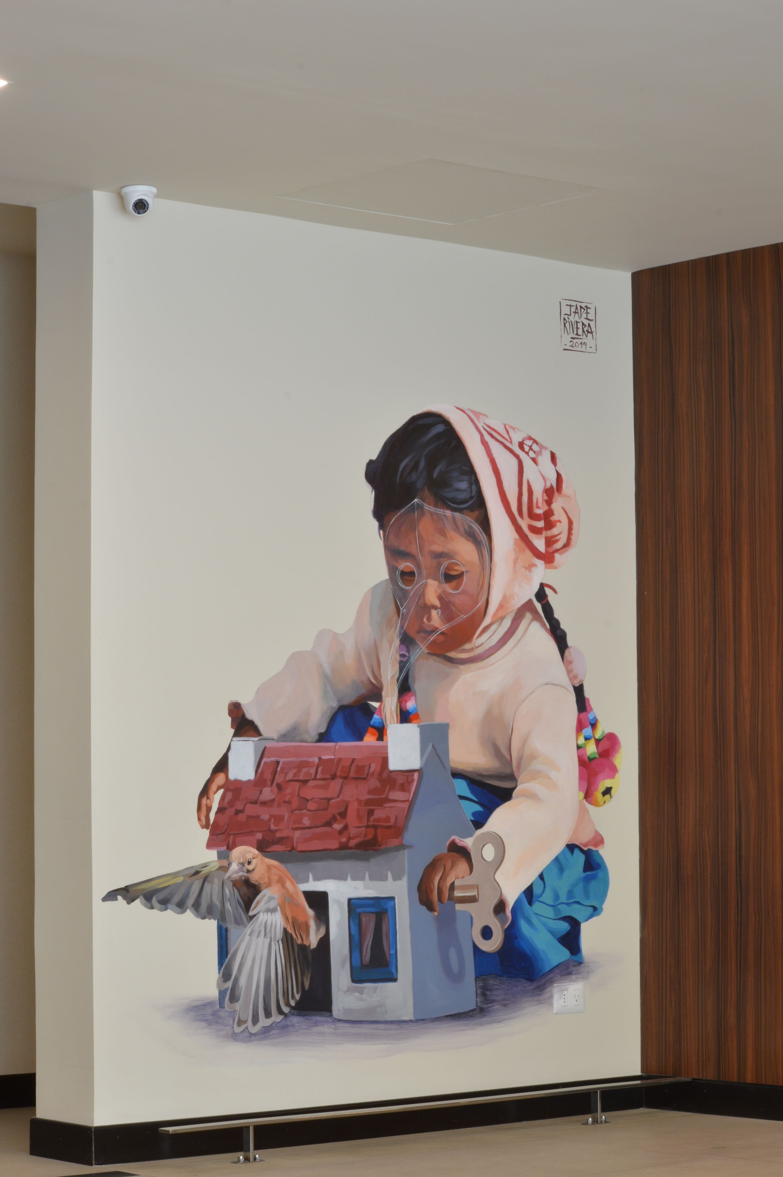 Un gran mural que muestra a un niño jugando con un pájaro y una casa.